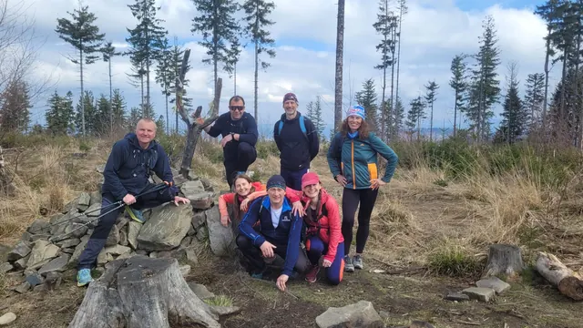 Skupina turistů na kamenitém vrcholu v Beskydech