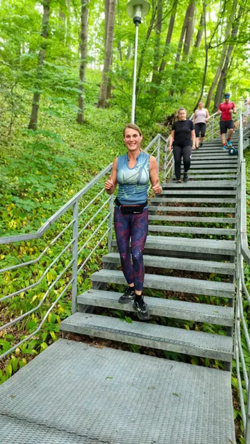 Usměvavá běžkyně na schodech ukazuje palce vzhůru